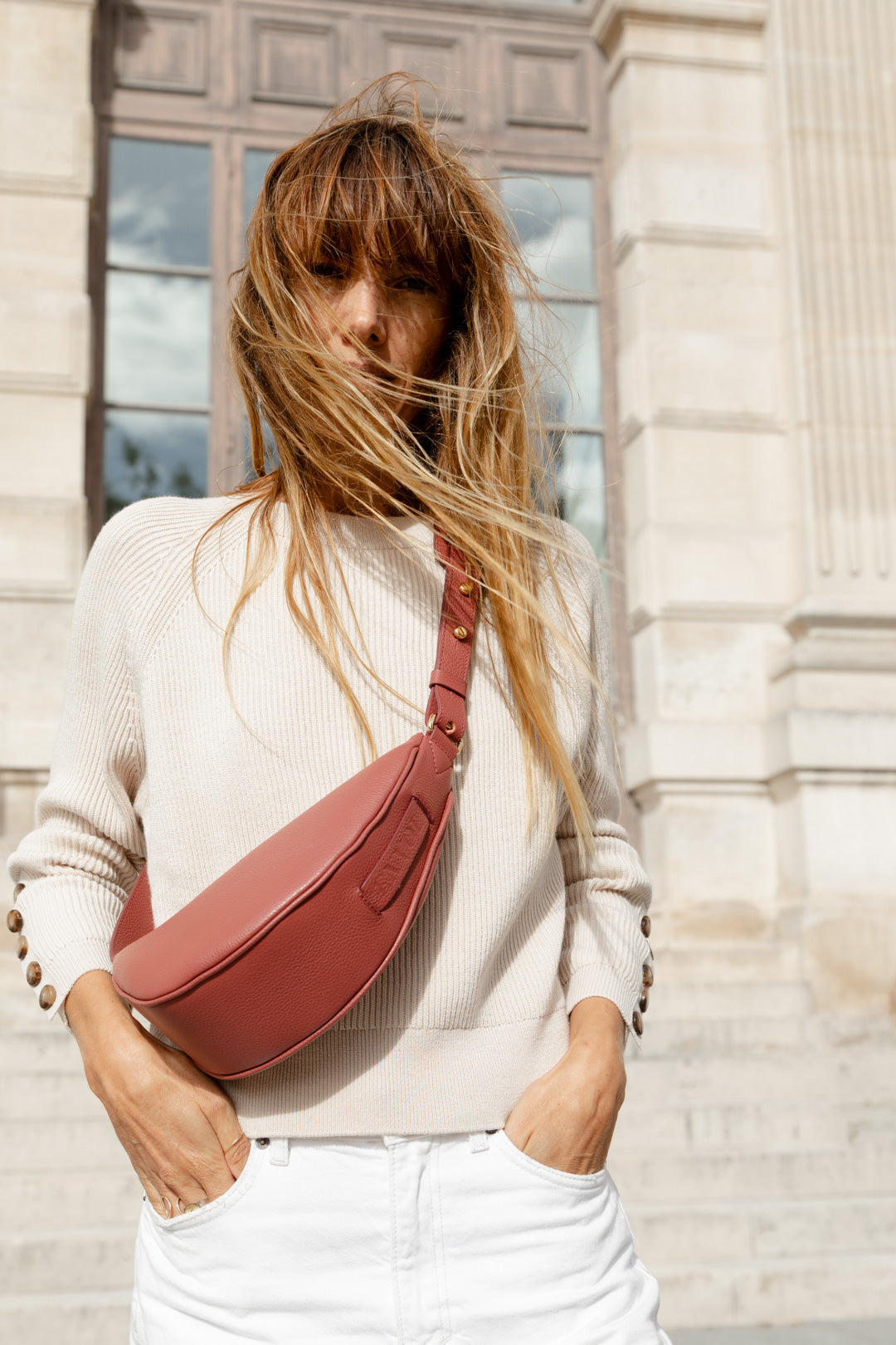 Femme portant le mini sac banane Lou ENVOL bois de rose en ville, de face #Couleur_Bois de Rose