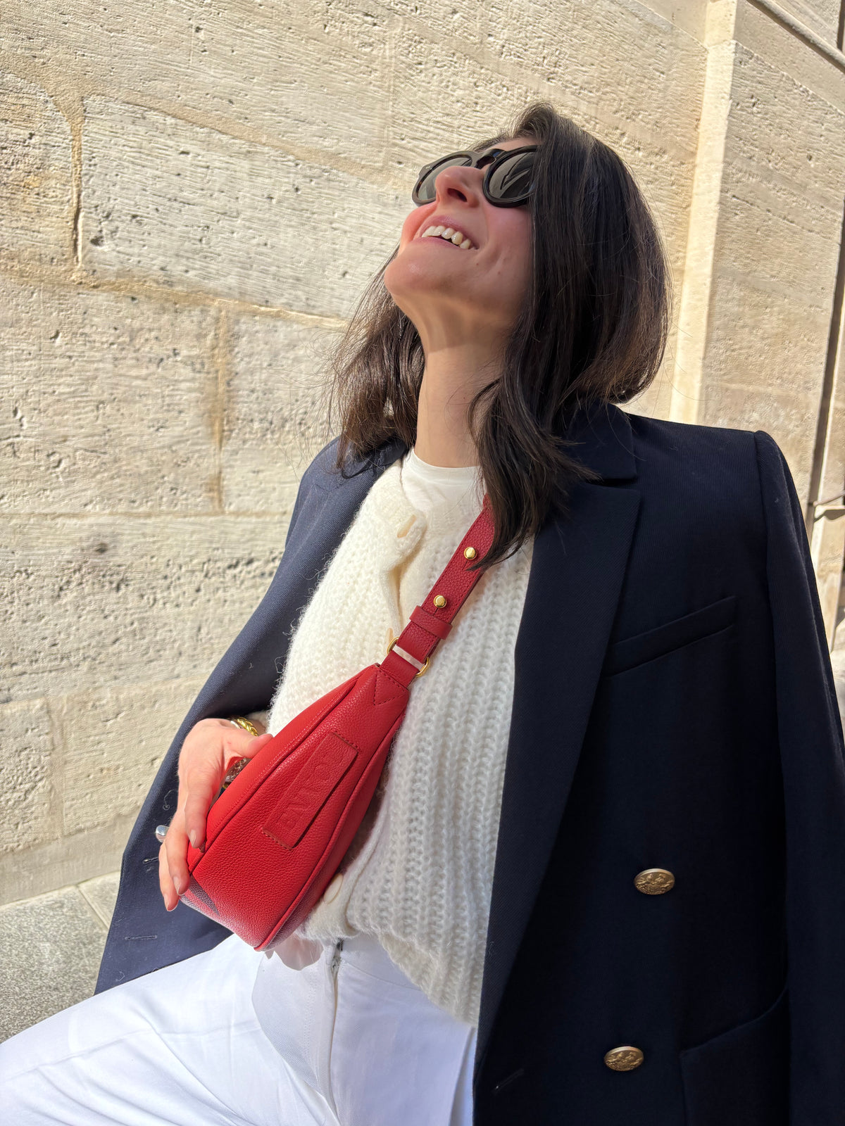 Femme portant le mini sac banane Lou ENVOL rose corail avec une veste bleu marine #Couleur_Rose Corail