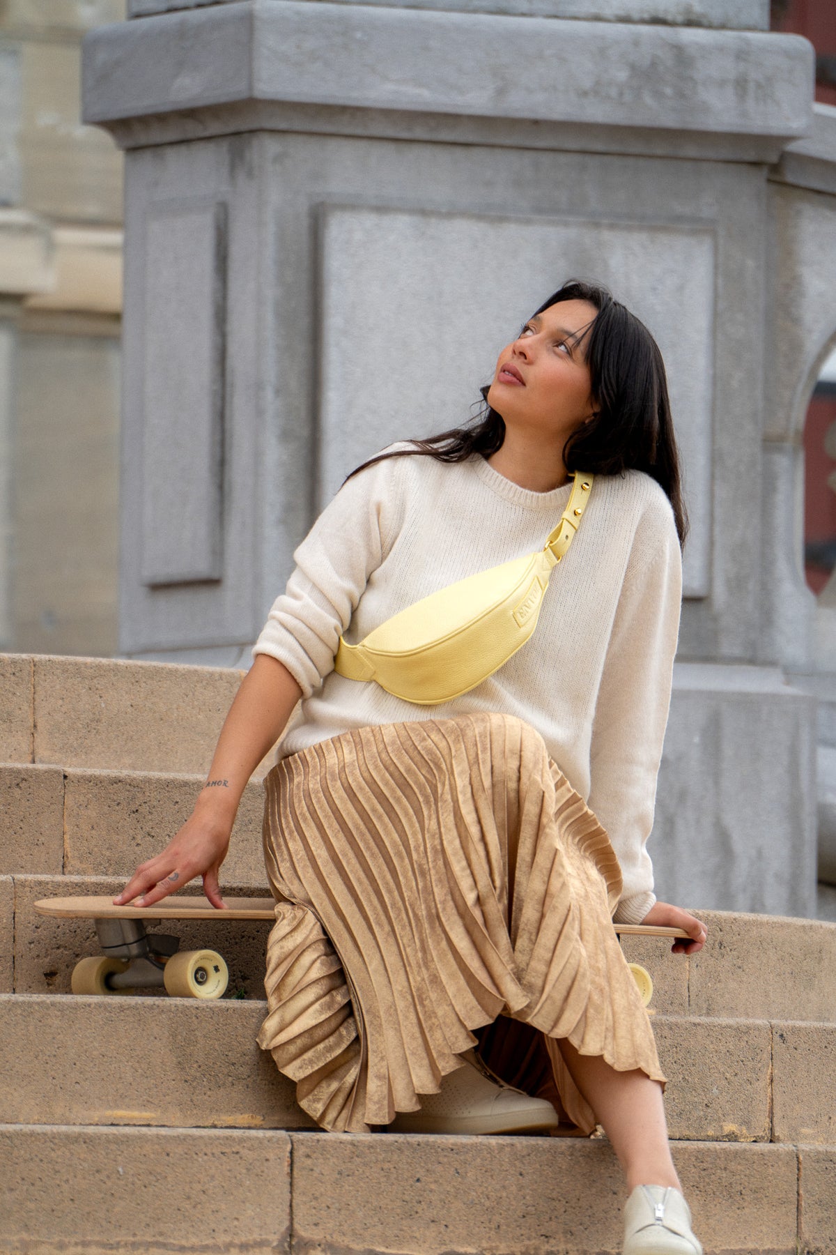 Femme portant le mini sac banane Lou ENVOL jaune pastel dans un escalier #Couleur_Jaune Pastel