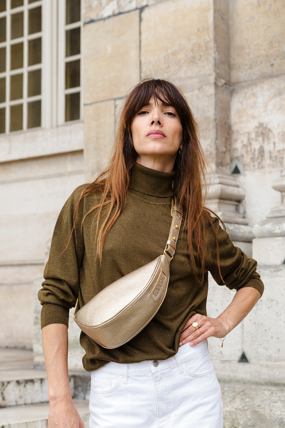 Femme portant le mini sac banane Lou ENVOL doré avec un pull kaki #Couleur_Gold