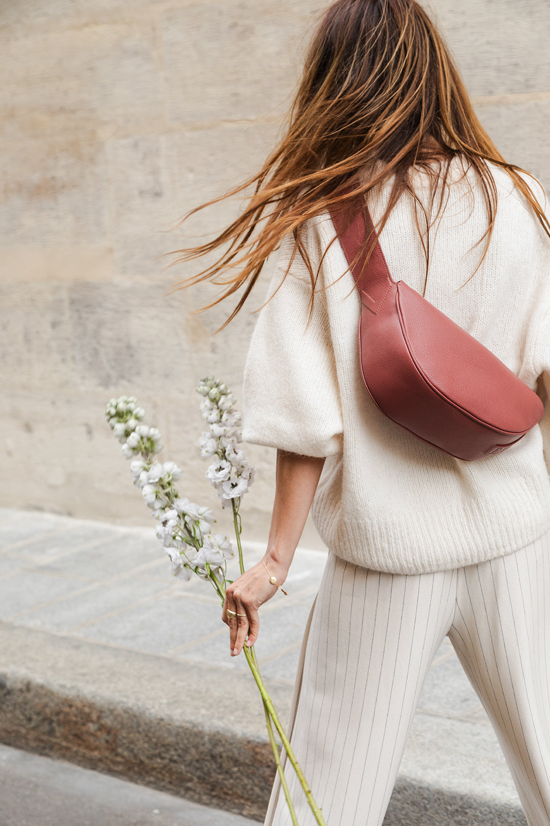 Femme portant le sac banane Thelma ENVOL bois de rose avec des fleurs #Couleur_Bois de Rose