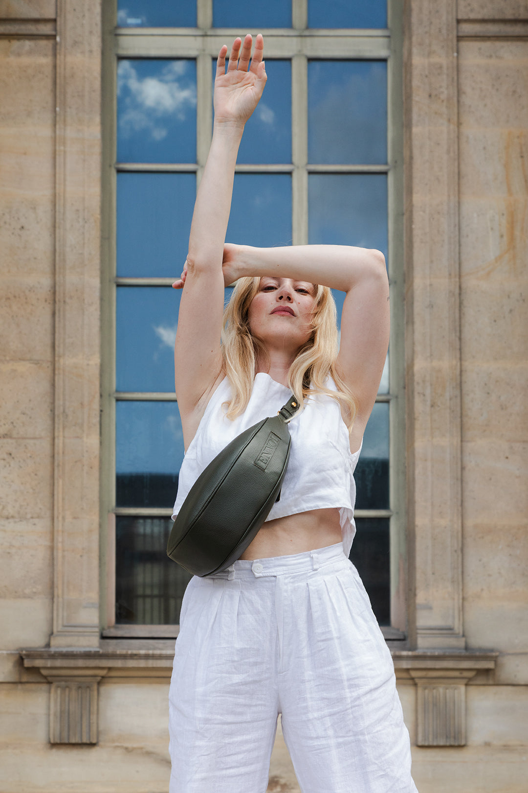 Femme portant le sac banane Thelma ENVOL vert anglais devant une porte #Couleur_Vert Anglais