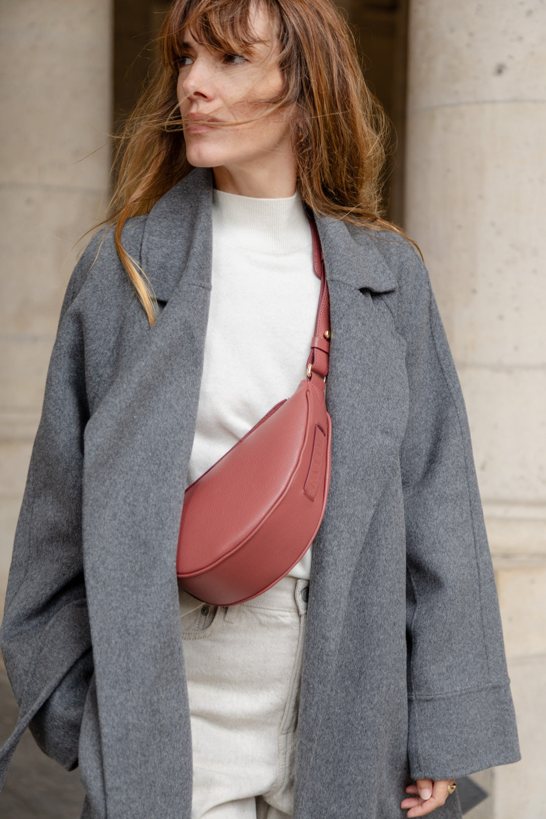 Femme portant le mini sac banane Lou ENVOL bois de rose avec un manteau gris #Couleur_Bois de Rose