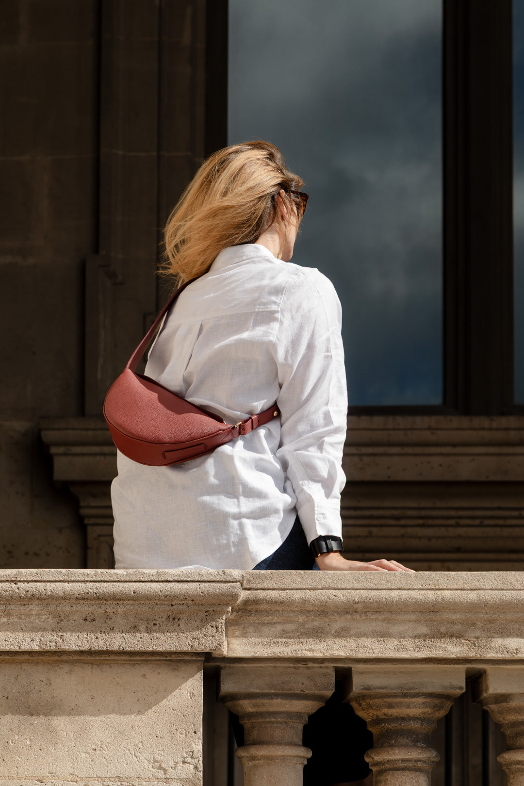 Femme portant le mini sac banane Lou ENVOL bois de rose assise #Couleur_Bois de Rose
