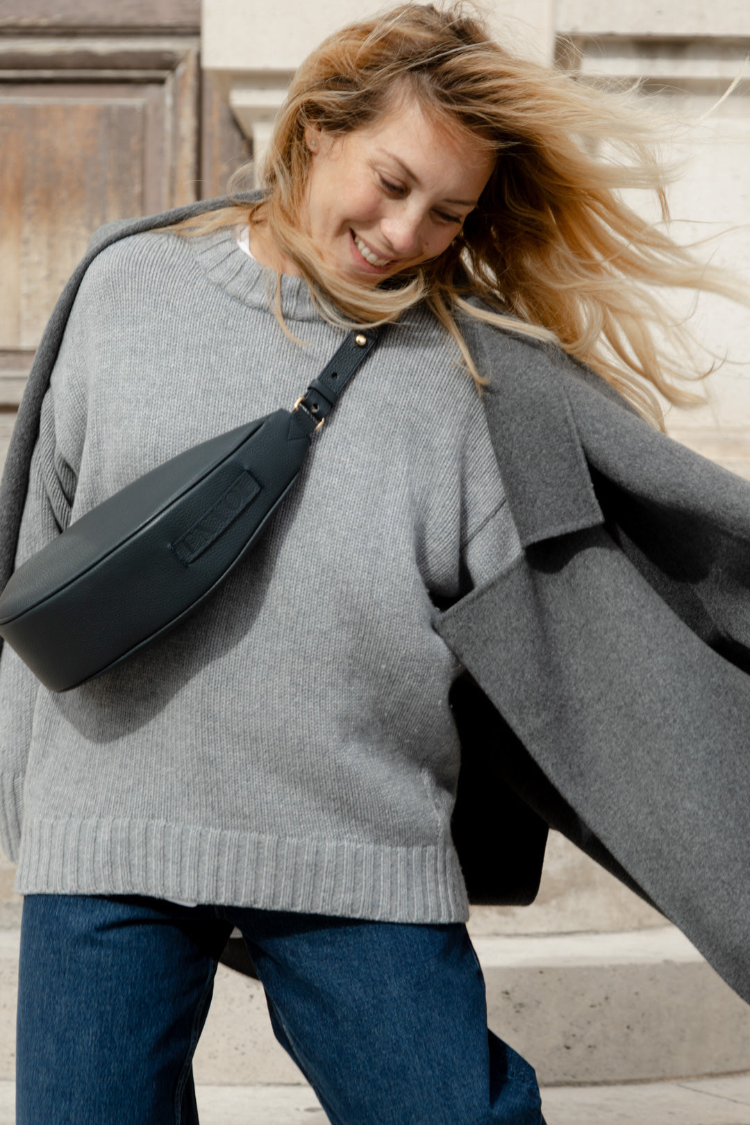 Femme portant le sac banane Thelma ENVOL bleu de cendre avec un pull gris #Couleur_Bleu de Cendre