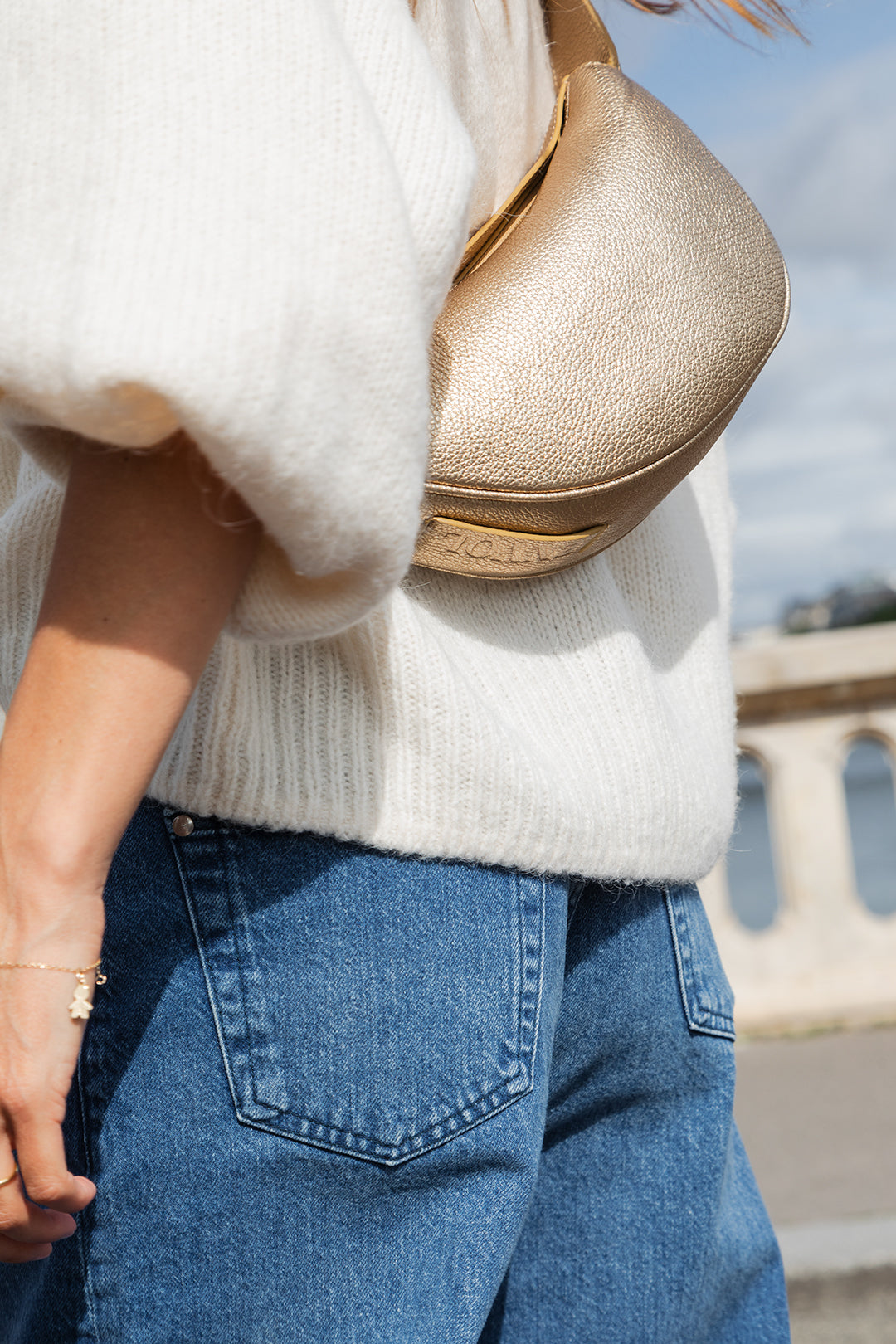 Femme portant le mini sac banane Lou ENVOL doré avec un jean #Couleur_Gold