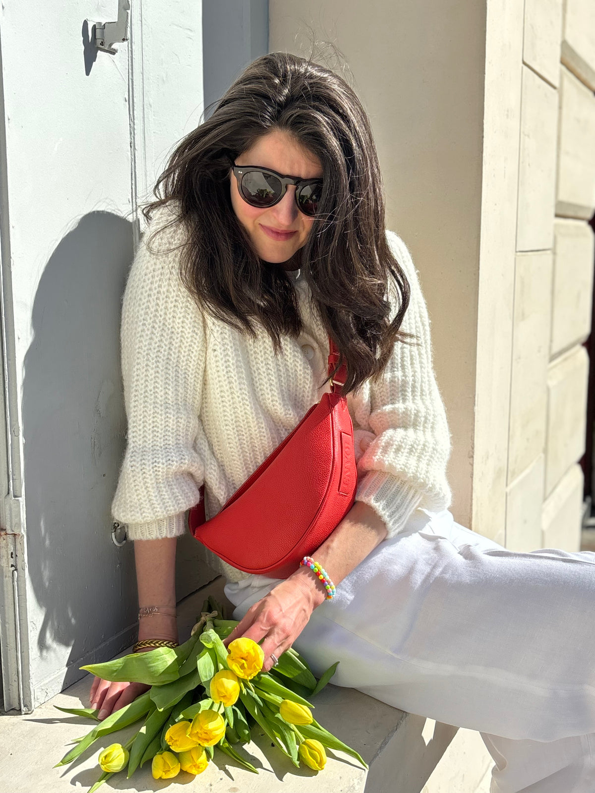 Femme portant le mini sac banane Lou ENVOL rose corail avec des fleurs jaunes #Couleur_Rose Corail