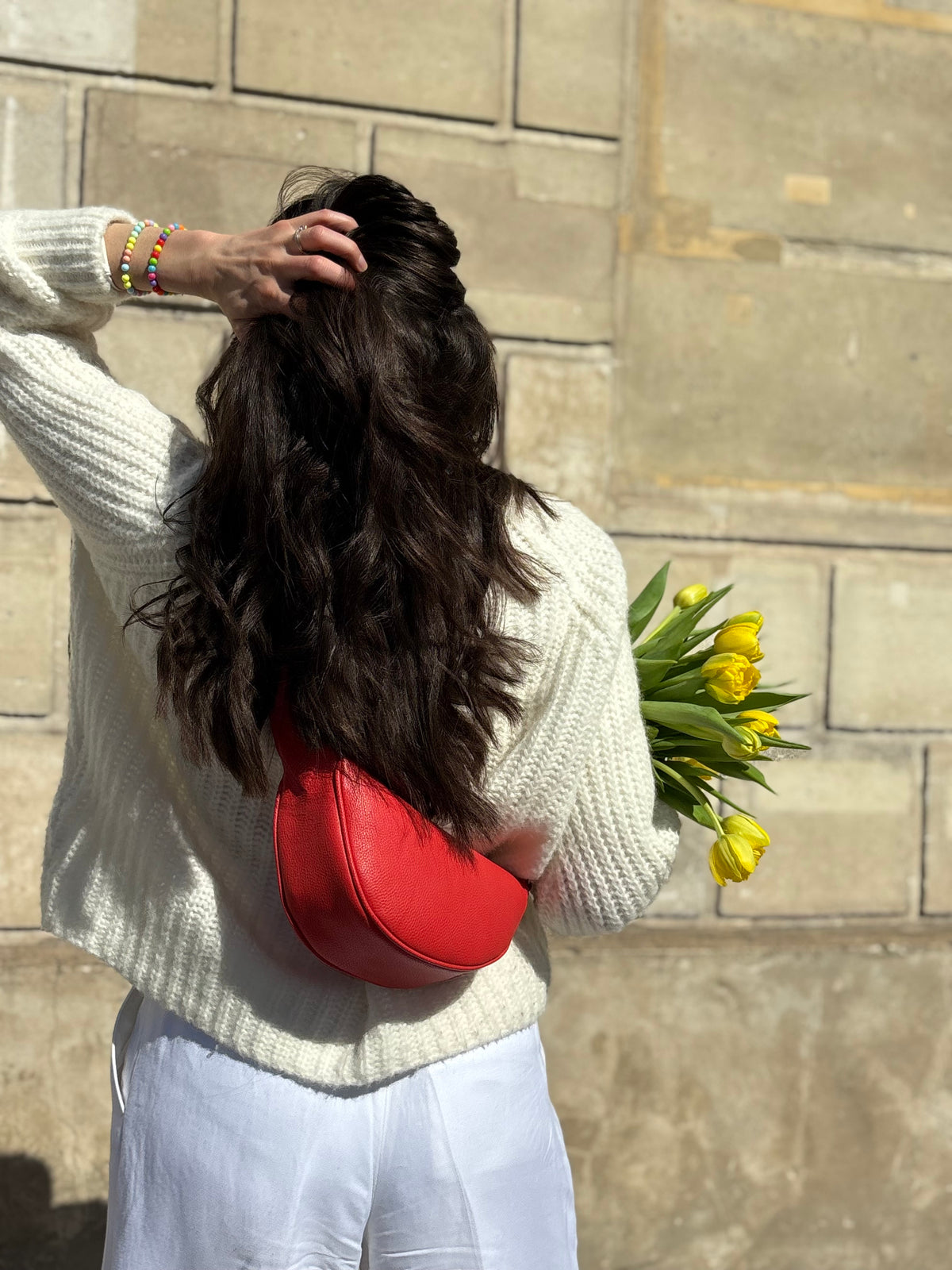 Femme portant le mini sac banane Lou ENVOL rose corail avec des fleurs #Couleur_Rose Corail