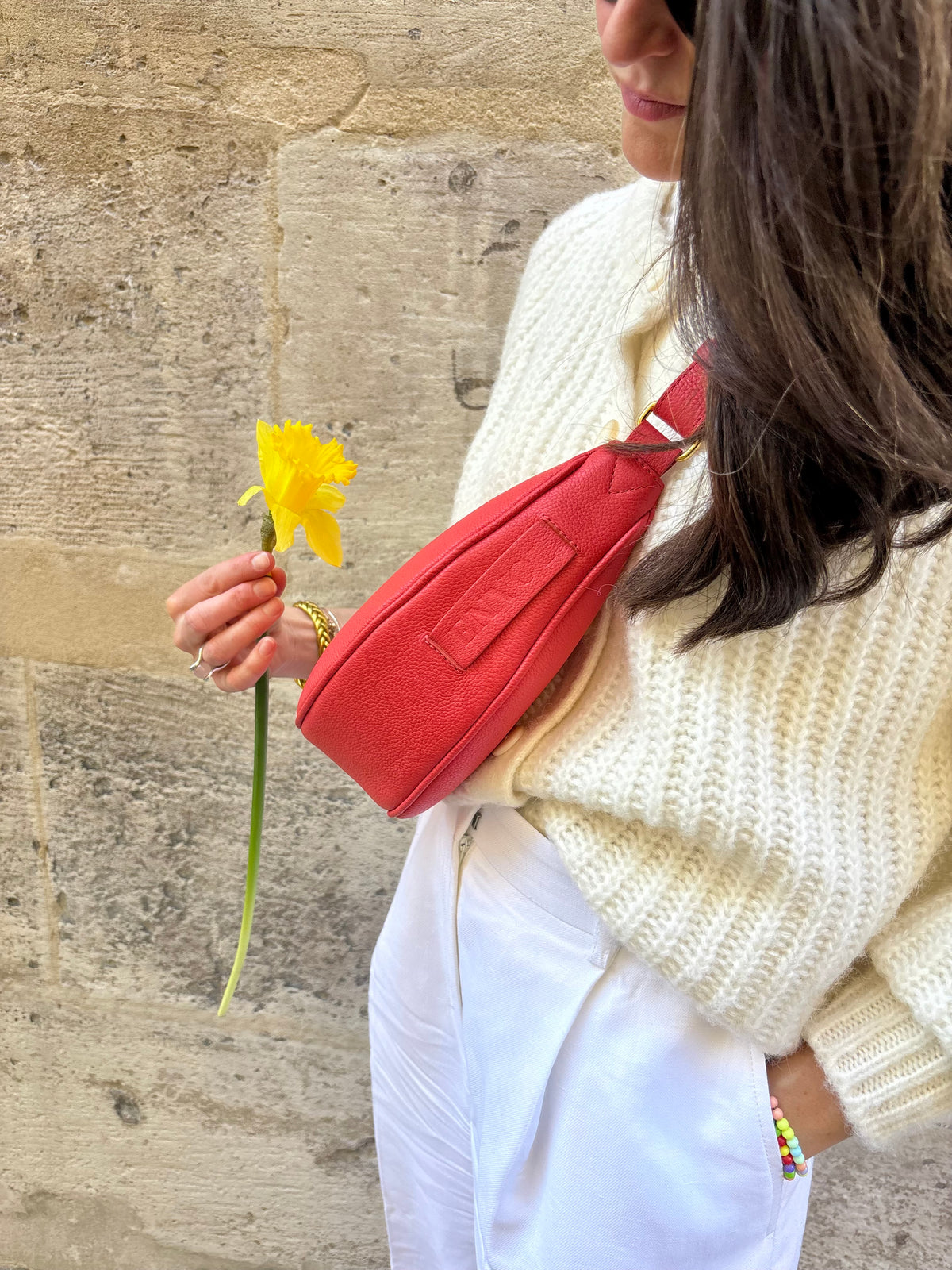 Femme portant le mini sac banane Lou ENVOL rose corail avec une fleur #Couleur_Rose Corail